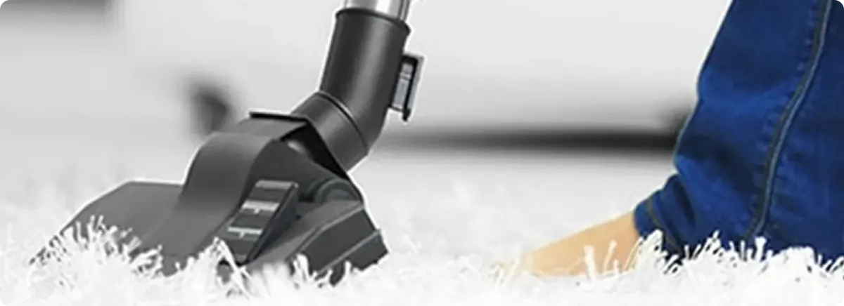 Close-up of a professional vacuuming a white carpet in Erie.